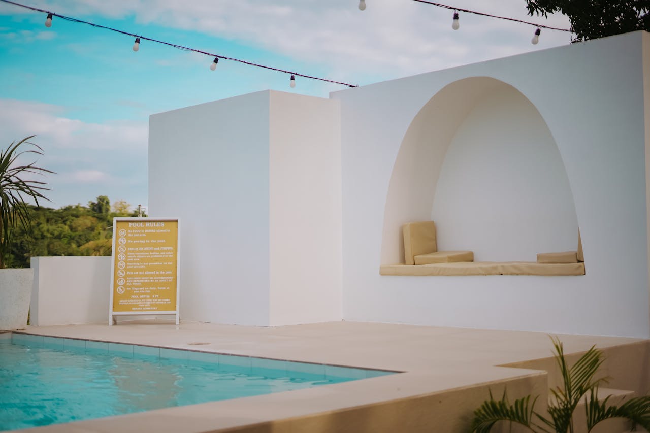 A luxurious resort with a relaxing poolside setup under a clear summer sky.